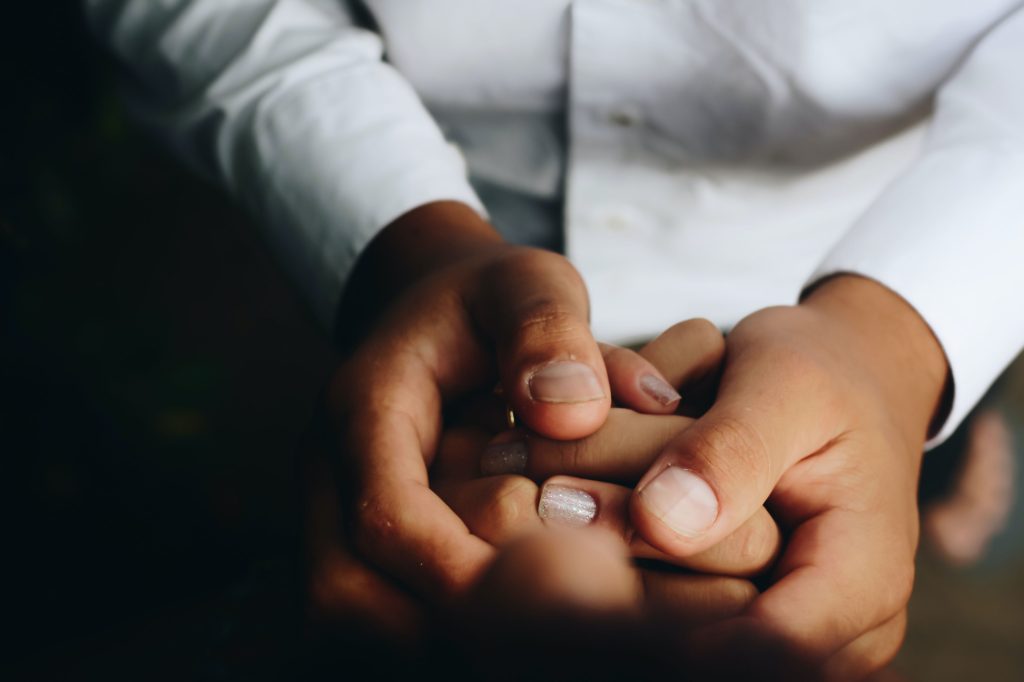 Close-up image of a pair of hands clasped comfortingly around another pair of hands